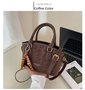 Gros plan du sac à main léopard avec bandoulière en cuir et détail de charme vintage