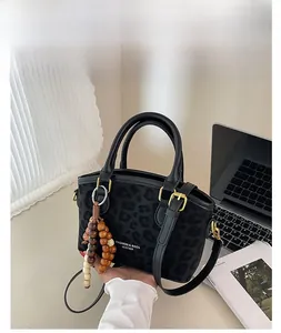 Détail du sac à main noir à motif léopard avec pendentif en perles de bois chic
