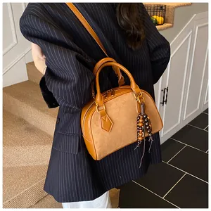 Detail of tan faux leather shell bag with wooden bead charm and crossbody strap