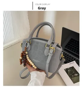 Détail du sac à main gris en similicuir avec breloque en bois et finitions dorées