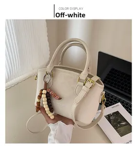 Vue détaillée d'un sac en similicuir beige avec pendentif en bois et ferrures dorées