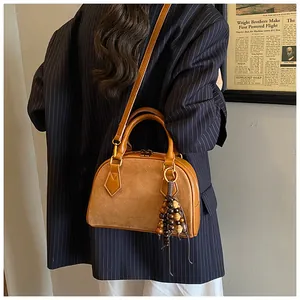 Detail of vintage brown shell bag with suede texture and wooden bead tassel accessory