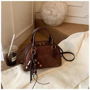 Detail of retro brown shell bag showing leather textures and wooden bead tassel ornament