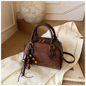 Macro view of vintage brown Boston bag featuring mixed textures and tassel detail