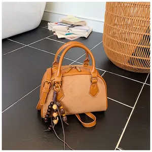 Detailed view of a brown patchwork Boston bag featuring suede texture and wooden bead tassel