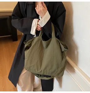Army green nylon tote bag with wide strap shown on model for a casual daily look