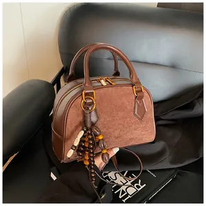 Detailed macro view of a vintage brown Boston handbag with wooden bead tassel and gold zipper