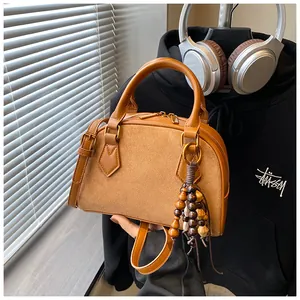 Detail of brown Boston handbag with leather splicing and colorful wooden bead tassel