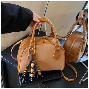 Detail of caramel boston bag with leather suede patchwork and wooden bead charm