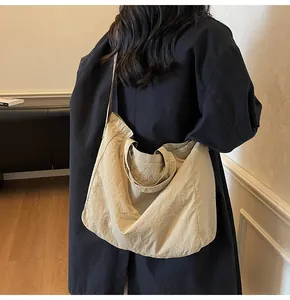 Rear view of a model wearing a large beige nylon tote bag with adjustable shoulder straps
