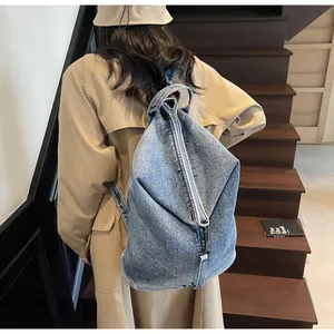Vue détaillée du sac à dos en denim délavé avec une structure pliée triangulaire unique