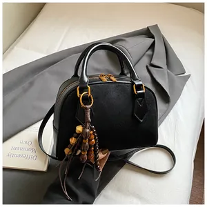Detailed close-up of a black vintage shell bag with gold hardware and bead charm
