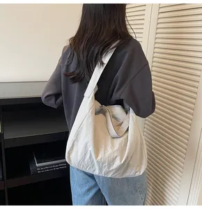Model wearing a large light grey pleated canvas tote bag with a wide shoulder strap