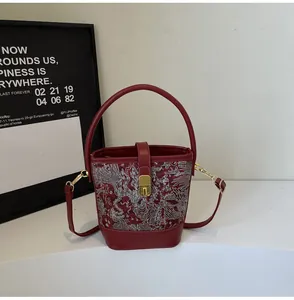 Detail of red bucket bag with traditional embroidery, metal lock and round handle