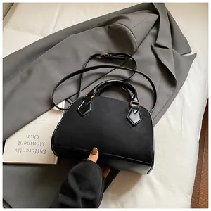 Detail of black semi-circular shell bag with matte leather mix and gold metal hardware