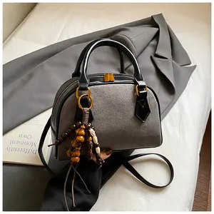 Detail of gray suede Boston bag with black leather handles and vintage wooden bead charm