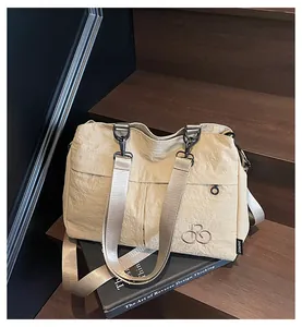 Vue macro du sac fourre-tout en nylon beige avec de larges bretelles sur des marches