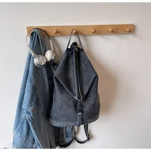 Détail du sac à dos en denim gris foncé lavé suspendu avec un casque au style décontracté