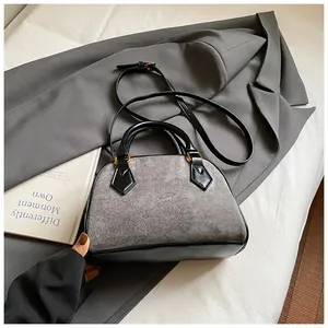 Close-up of retro shell bag featuring grey textured fabric and black leather trim