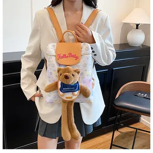 Detail of cute plush bear charm and Hello Baby embroidery on stylish cartoon backpack