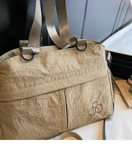 Detailed macro view of khaki wrinkled nylon fabric and branded embroidery on the tote bag