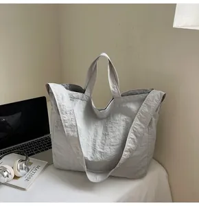 Detail of light grey textured canvas tote bag featuring dual handles and a long shoulder strap