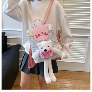 Detail of pink and white backpack featuring Hello Baby embroidery and a plush bear charm