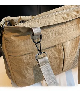 Detail of durable black metal hardware and reinforced nylon fabric on khaki tote bag