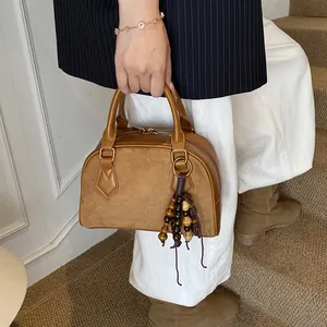 Vintage brown suede shell handbag with wood bead tassel shown from a side view