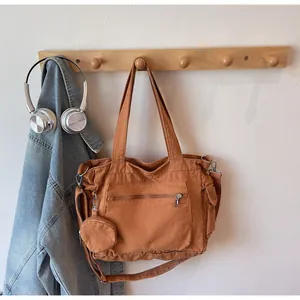 Detail of tan canvas tote bag with detachable coin purse and adjustable strap on a hook