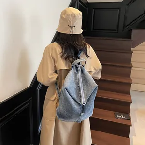 Sac à dos vintage en denim délavé bleu à grande capacité porté par un mannequin chic