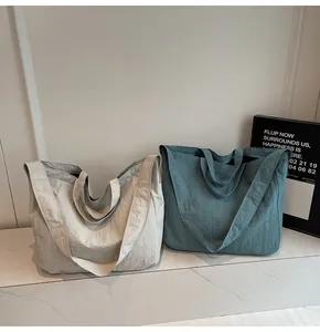 Detail of large canvas tote bags in off-white and grey-blue with double handle structure