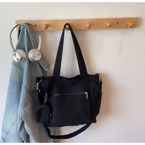 Detail of black canvas tote bag hanging with round coin purse and large zipper pocket