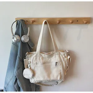 Detail view of canvas tote bag with front zipper pocket and round coin purse attachment