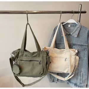 Detail of canvas tote bags with adjustable straps and front zipper pocket on metal hangers