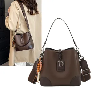 Detalle de bolso bucket marrón oscuro con grano lichi, cuentas de madera y colgante