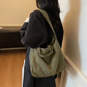 Olive green canvas tote bag with wide shoulder strap shown on model for casual daily use