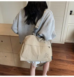 Détail du sac de voyage en nylon kaki avec logo brodé et bandoulière réglable