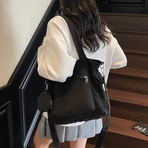 Large black canvas tote bag with round coin purse worn by a model on a wooden staircase