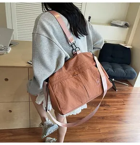 Détail du sac cabas en nylon rouge brique avec bandoulière rose et crochets