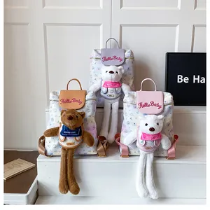 Detailed view of floral backpacks in purple, brown and pink with plush teddy bear charms
