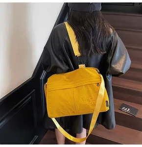 Détail du sac fourre-tout en nylon jaune vif avec bandoulière réglable et broderie du logo