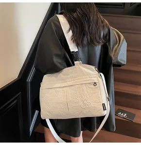 Detail of white wrinkled nylon crossbody bag featuring black SHUNUO label and metal buckle