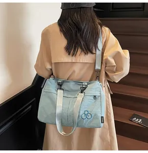 Détail du sac cabas en nylon bleu clair avec broderie vélo et large bandoulière