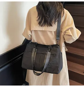 Détail du sac fourre-tout en nylon noir avec logo et bandoulière large réglable