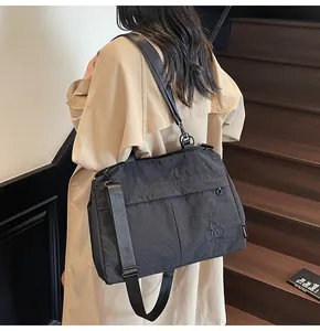 Détail du sac cabas en nylon noir texturé porté sur un trench-coat beige élégant