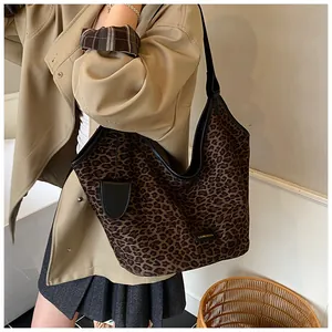 Détail du sac cabas léopard avec bordure en cuir noir et pendentif latéral élégant
