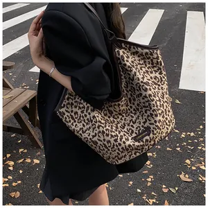 Détail du sac cabas léopard avec bordures en cuir marron et étiquette logo rétro