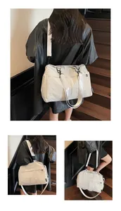 Détail du sac cabas blanc avec étiquette de marque et tissu synthétique texturé