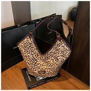 Détail du sac cabas léopard avec bordure en cuir marron et plaque de marque en métal